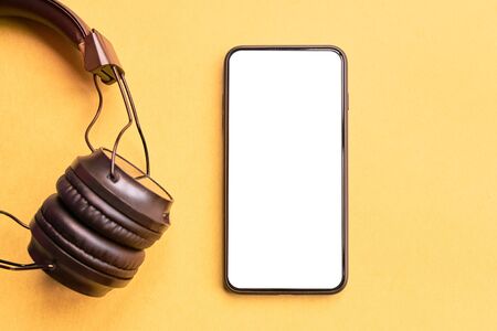 Wireless Headphones and smartphone on colorful background. Isolated Phone and earphones for music sound on yellow background.の写真素材
