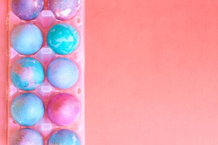 Painted Easter eggs with space intergalactic pattern in stand on coral backgroundの写真素材