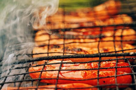 Fried food. Close up barbecue grill with meat and sausages cooking during summer.の写真素材