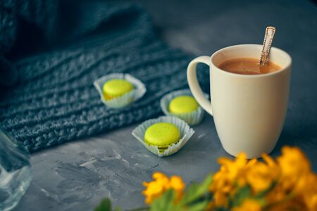 Hot coffee with milk or cream and yellow macaroons on the loft table in a romantic setting with chrysanthemums nearbyの写真素材