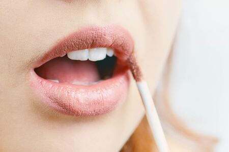 The woman paints her lips. Beige lipstick color.の写真素材