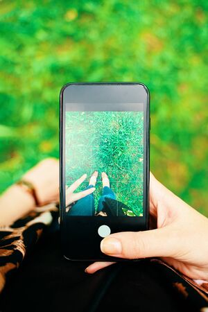 Personal Perspective pov of woman taking photograph with the mobile phone smartphone with hand and legs in the frameの写真素材