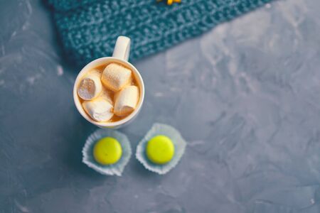 Hot coffee with marshmallow and milk or cream and yellow macaroons on the loft table in a romantic setting with chrysanthemums nearbyの写真素材