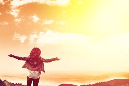 Beauty woman outdoors enjoying nature. Image of a girl in a field standing in the distance with her...