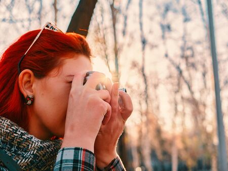 Person with camera in autumn. Red hair woman with retro photocamera. photography classesの写真素材