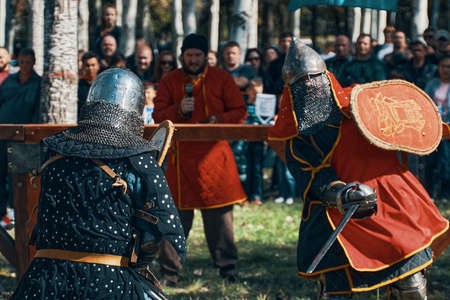 Reconstruction of medieval tournaments of knights. Knights in armor and helmets, fighting with swords and shields in the arena. Festival of historical clubs. Bishkek, Kyrgyzstan - October 13, 2019のeditorial素材