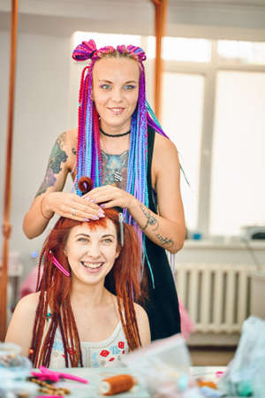 Barber braids dreadlocks. Process of braiding the master weaves braids on her head in a beauty salon...