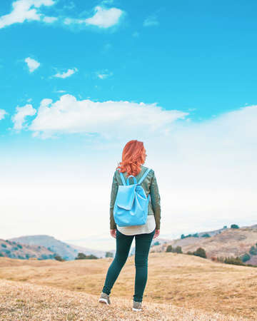 Beauty woman outdoors enjoying nature. Woman traveler hipster with backpack and looking forward at amazing mountains and valley view.の写真素材