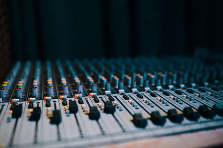 Remote sound engineer. Many buttons of black audio mixer board console for sound producer. Music equipment. Close-upの写真素材
