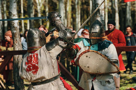 Battle of knights in armor on swords in front of the audience. Festival of historical clubs in the Park. Reconstruction of medieval battles. Bishkek, Kyrgyzstan - October 13, 2019のeditorial素材