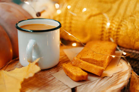 Pumpkin juice and freshly baked carrot cake on a wooden tray. Orange pumpkin, knit sweater and yellow autumn fallen leaves.の写真素材