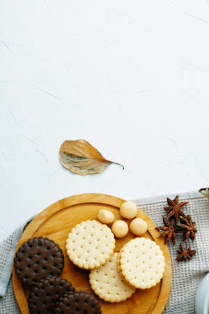 Cookies and candy on wooden tray. White table with kitchen tablecloth, sweets and star anise. Autumn leaf on table. The concept of Christmas, Thanksgiving and Halloween.の写真素材
