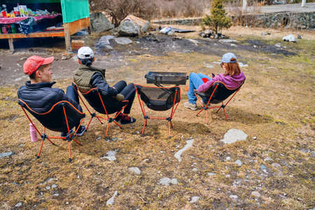 Team building on nature. Group of people resting on chairs after a hike. Resort area for picnics. Tourists on vacation in the mountains. Bishkek, Kyrgyzstan - April 9, 2019.のeditorial素材