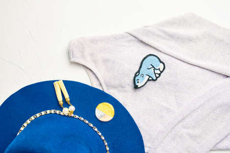 Flat lay of a gray jacket with a brooch and a blue hat. Brooch made of beads in the shape of a blue bear. Handmade, craft, jewelry made of beads.の写真素材