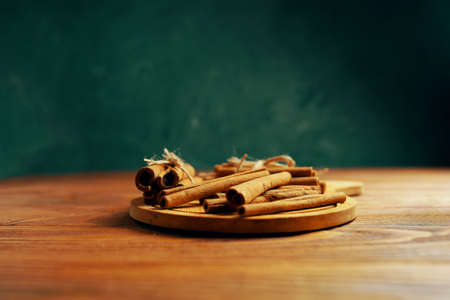 Cinnamon sticks on a tray. Spice on a wooden table. Dark green background. Added to mulled wine or Christmas drinks and baked goods.の写真素材