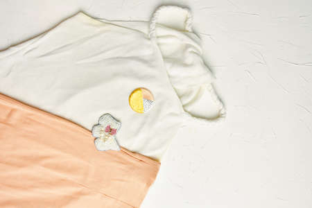 Top view of white top with brooch and pink skirt on white concrete background. Brooch made of beads, pearls and mother-of-pearl beads. Handmade, craft. Costume jewelry in the form of dog with bow.の写真素材