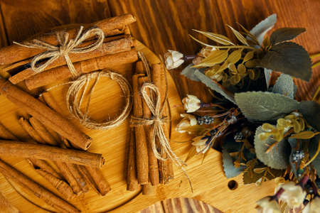 Cinnamon sticks on a tray. Spices and a bouquet of flowers on a wooden table. Add to mulled wine or Christmas drinks and pastries. string.の写真素材
