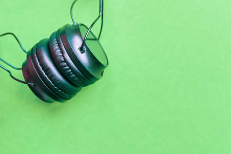 Headphones on colorful background. Earphones on green background. Device for listening to music, podcasts, or audiobooks.の写真素材