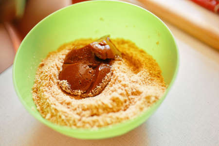 Mixing ingredients for pie. Boiled condensed milk with ground cookies. The base for cake. Preparation of biscuits. Baking background.の写真素材