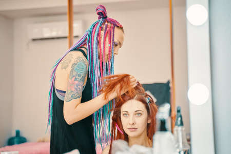 Barber braids dreadlocks. Beautiful girl making trendy braids dreadlocks. Bishkek, Kyrgyzstan - July 04, 2019のeditorial素材