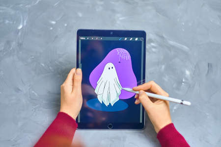 Woman Illustrator draws Ghost on iPad Pro in procreate program using apple pencil. Digital Illustrator. Freelance work as a designer. Bishkek, Kyrgyzstan - January 21, 2019.のeditorial素材