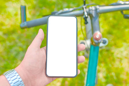 Man with a smartphone on a Bicycle workout on offroad. Mockup. Trendy photo. Flat lay concept: devices for everyday life. Phone with blank screen, copy space.の写真素材