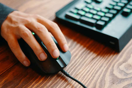 Human hand on computer mouse. Computer set on wooden background. Streaming online games on internet.の写真素材