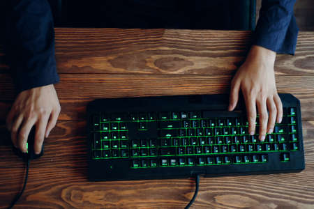 Gaming keyboard with neon lighting. Computer set. Hand typing on computer keyboard, with application icons on button. Application Programming Interface.の写真素材