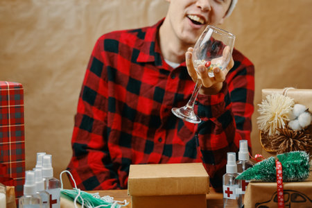 Guy in plaid shirt holds a glass with drugs and vitamins. Man in Christmas decorations. Table with...