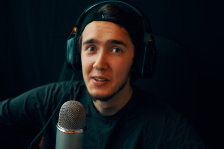 Radio show or audio podcast concept. Man with headphones, microphone and a funny face tells a story in the studioの写真素材