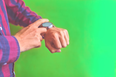 Man with smart watch on green background. Concept for business, multi payment, lifestyle using. Smartwatch - modern digital gadget with empty display, copy space.の写真素材