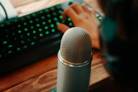Man with headphones is typing on the keyboard and podcasting with retro old microphone. Radio show or audio podcast concept.の写真素材