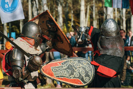 A knight in grey against a knight with a wolf on his shield. Sword fighting. Imitation of a jousting match in the arena. Festival of historical culture. Bishkek, Kyrgyzstan - October 13, 2019のeditorial素材