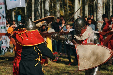 Knight in red and black against a knight with shield. Reconstruction of a medieval battle in the arena with the audience. Festival of historical clubs. Bishkek, Kyrgyzstan - October 13, 2019のeditorial素材