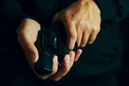 Mens hands check for bullets in revolver barrel. Reloading gun close-up. Guy prepares pistol for...