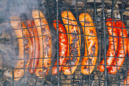 Barbecue with fiery sausages hotdog on the grill outdoor picnic preparing hot food to be served at a local outdoor fair on the picnic. Flat Layの写真素材