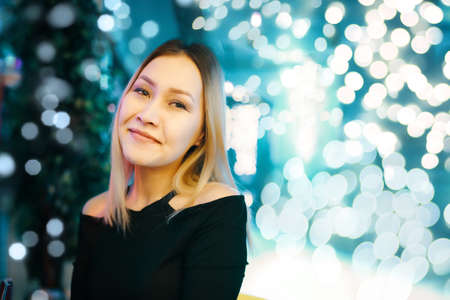 Portrait of awesome woman against background of bright lights. Female posing at camera in lounge bar. Copy space for text or advertisement. Night holiday party.の写真素材