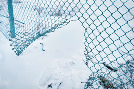 Hole in wire border fence. Unauthorized entry is prohibited. Maximum security detention facility. Illegal trespassing. Escape from prison or closed institution for mentally ill. Winter snowy weather.の写真素材