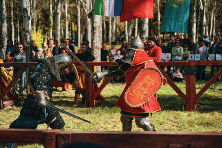 Battle of knights in the arena. Swords, shields, helmets and armor on the knights. Reconstruction of medieval battles. Festival of medieval culture. Bishkek, Kyrgyzstan - October 13, 2019のeditorial素材