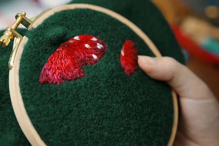 Womens hand embroidery mushroom hat in hoop on dark material. Close-up. Concept of needlework, hobby, leisure.の写真素材