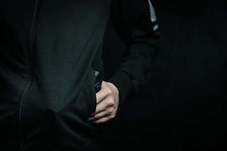 Guy is threatening with gun in his jacket pocket. Night thief and robber. Criminal hides weapon in...