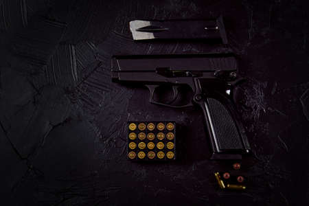 Flat lay of cartridges and gun on concrete background. Top view with copy space. Pistol and bullets...