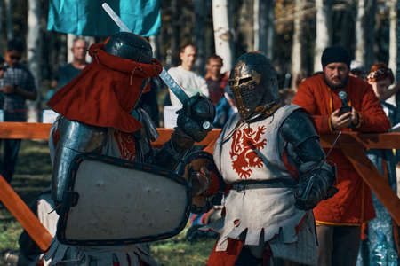 Two knights in armor imitate a sword fight. Festival of medieval culture in the Park. Reconstructions of historical battles. Bishkek, Kyrgyzstan - October 13, 2019のeditorial素材