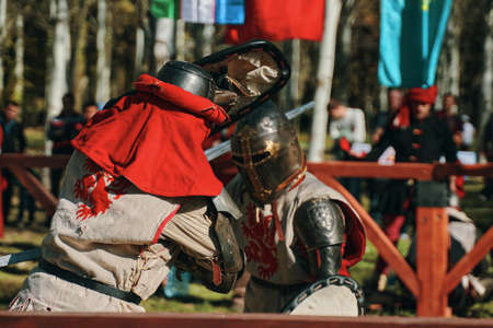 Two knights in armor imitate a sword fight. Festival of medieval culture in the Park. Reconstructions of historical battles. Bishkek, Kyrgyzstan - October 13, 2019のeditorial素材