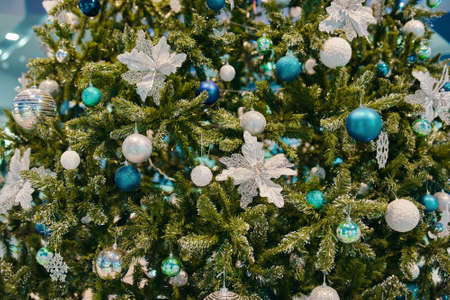 Christmas tree with festive ornaments. New Year atmosphere and aesthetic decorations. Silver flowers...