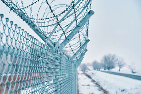 Close up of barbed wire fence on border in winter. Closing for quarantine. Private secured object...