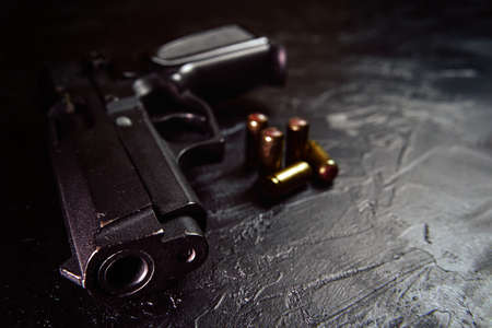 Black gun and bullets on table. Firearms on concrete background. Weapons and ammunition. Concept of crime and physical evidence. Pistol for defense or attack.の写真素材
