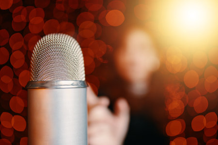 Close up with copy space of mic in concert hall. Retro microphone on stage and woman silhouette in black dress with bokeh light background. Night party in club or restaurant.の写真素材