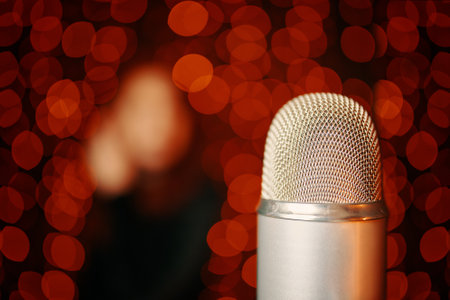 Retro microphone on stage and woman silhouette in black dress with bokeh light background. Close up with copy space of mic in concert hall.の写真素材