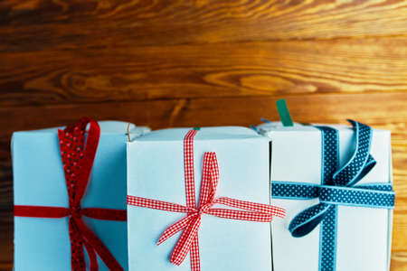Top view of gifts stack. White boxes with ribbons on wooden table. Festive still life. Preparing for Christmas. Composition for birthday or new year.の写真素材